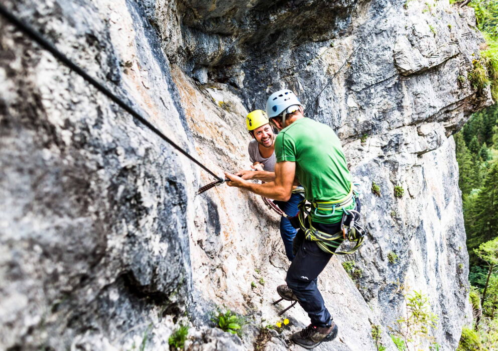 Zwei Freunde am Klettern an einer Felswand im Salzkammergut