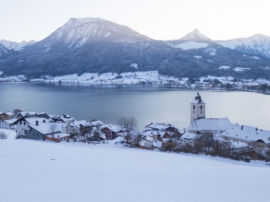Verschneiter Ort Sankt Wolfgang und weiße Berglandschaft