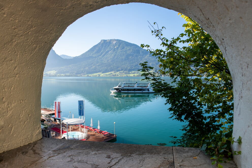 Frau sitzt auf dem Steg am Wolfgangsee und liest ein Buch