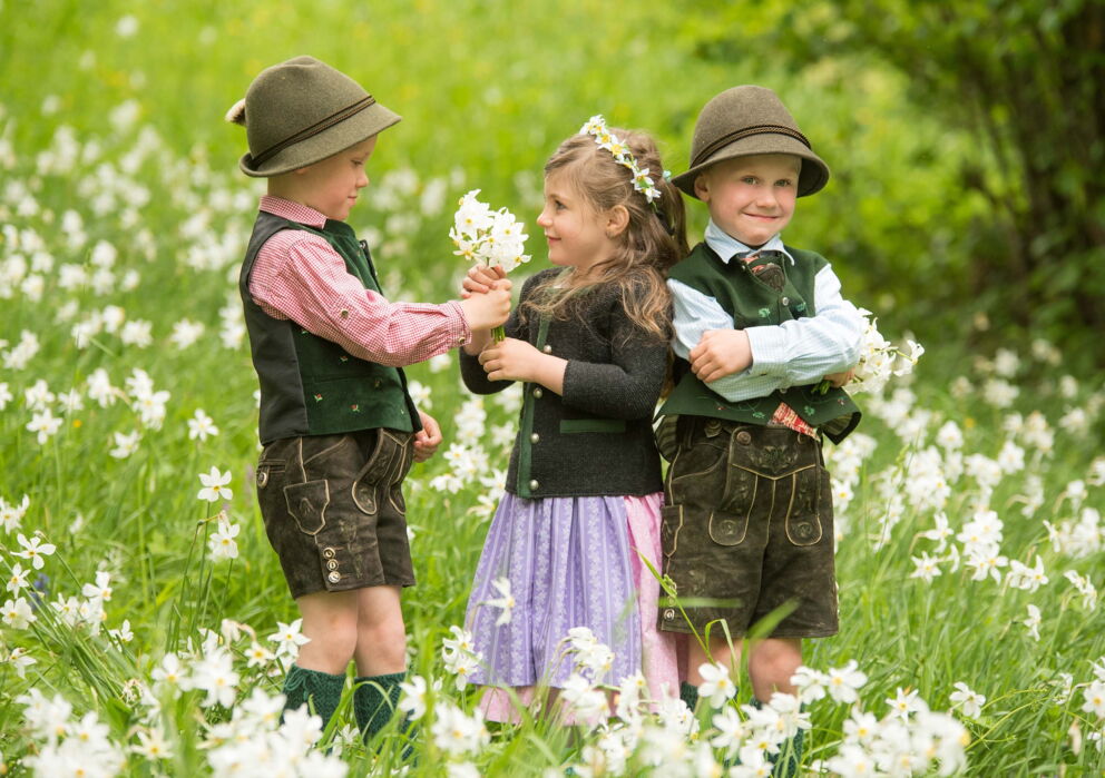 Kinder in einem Feld volle weißer Blumen in traditioneller Tracht gekleidet
