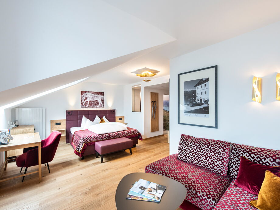 Brightly lit room in the Hotel Im Weissen Rössl with cosy bed and modern furnishing style