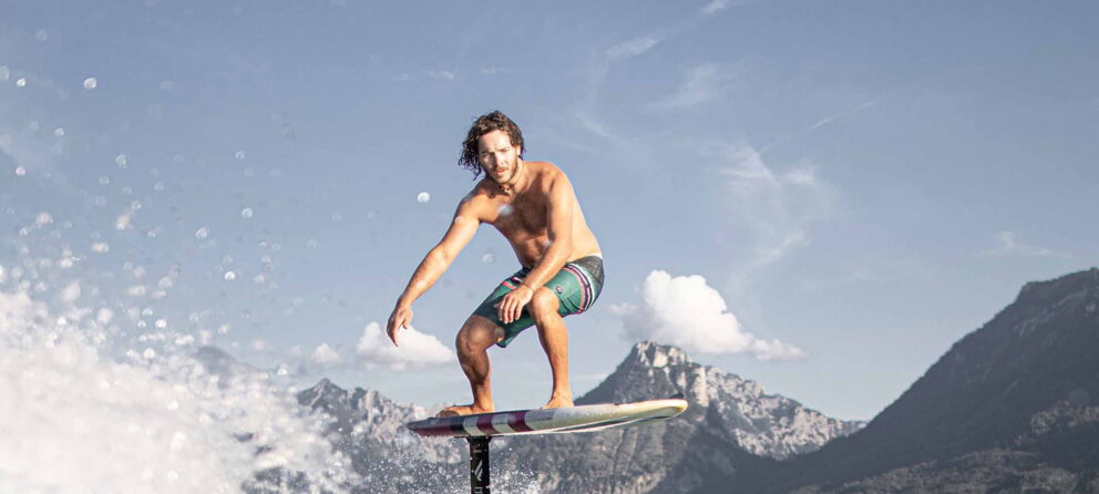 Mann am Surfen auf dem Wolfgangsee mit atemberaubender Bergkulisse
