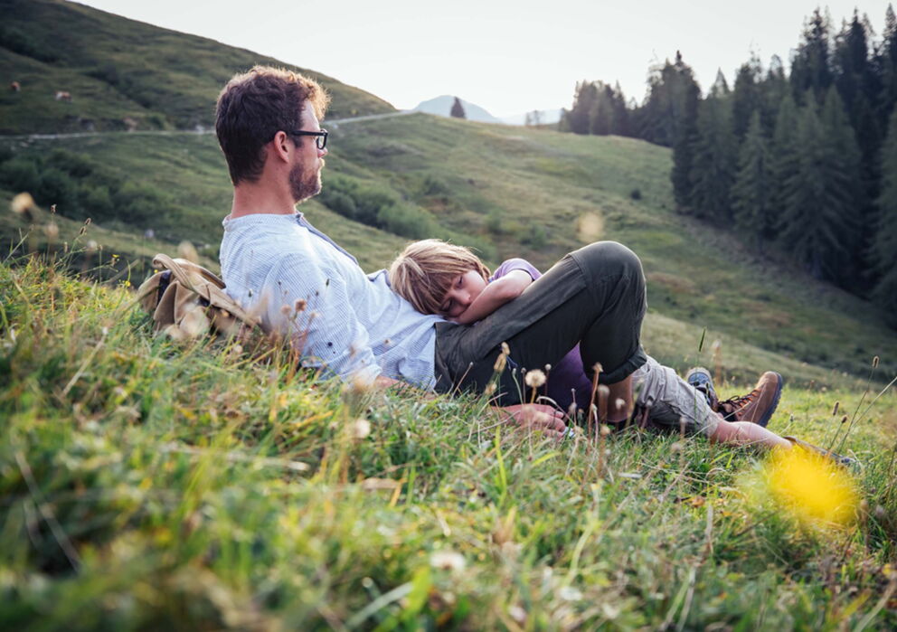 Vater und Tochter liegen im Salzkammergut im Gras und genießen die Natur
