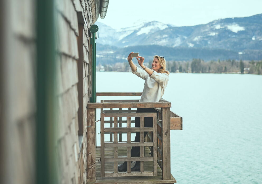 Woman photographing on a balcony by the lake.