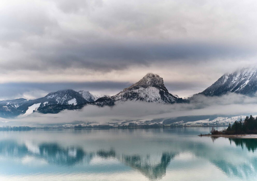 Der Wolfgangsee in Österreich im Winter mit schneebedeckter Bergkulisse und leichtem Nebel
