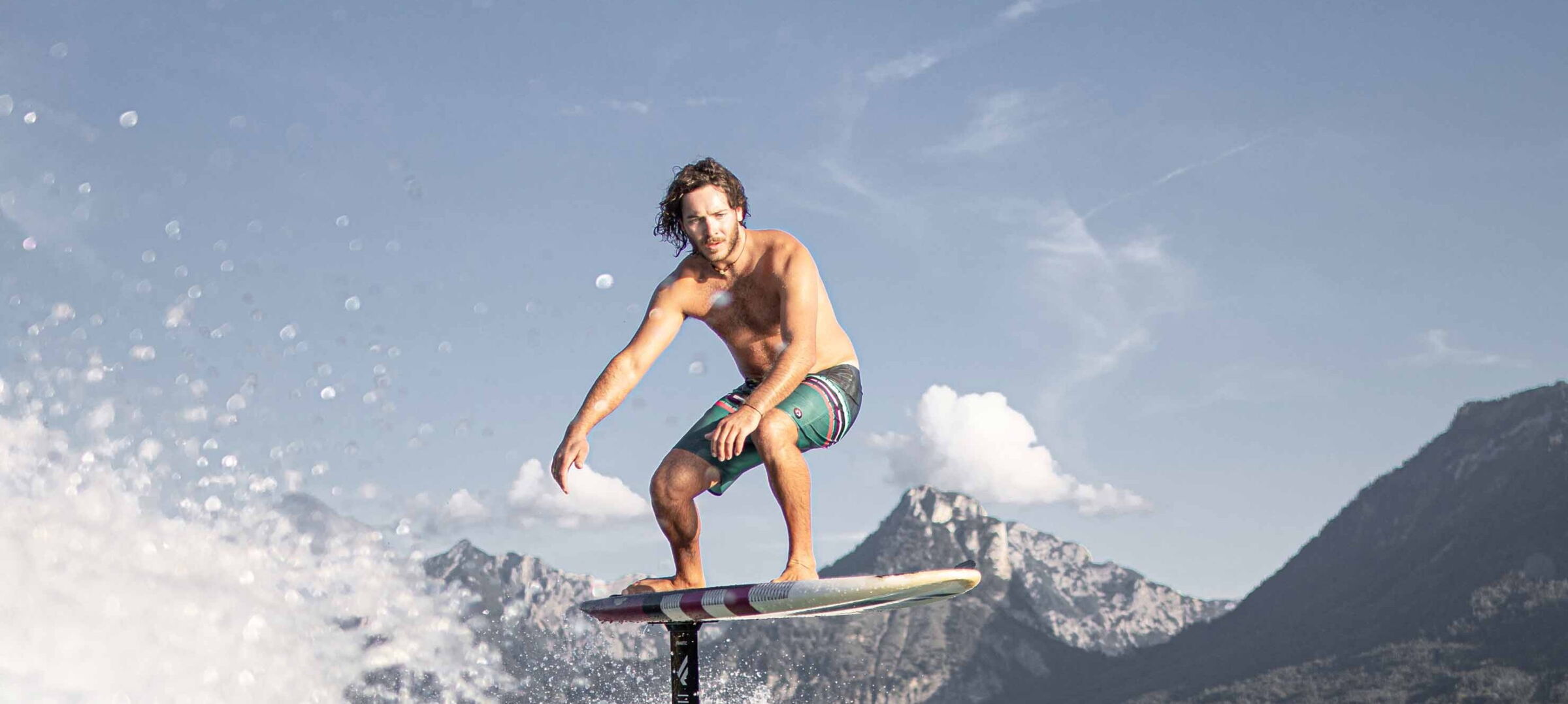 Mann am Surfen auf dem Wolfgangsee mit atemberaubender Bergkulisse