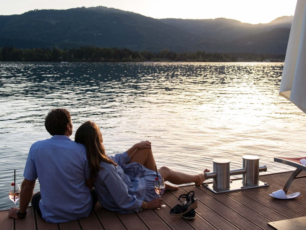 A couple in love sitting on the jetty of Lake Wolfgang watching the sunset.