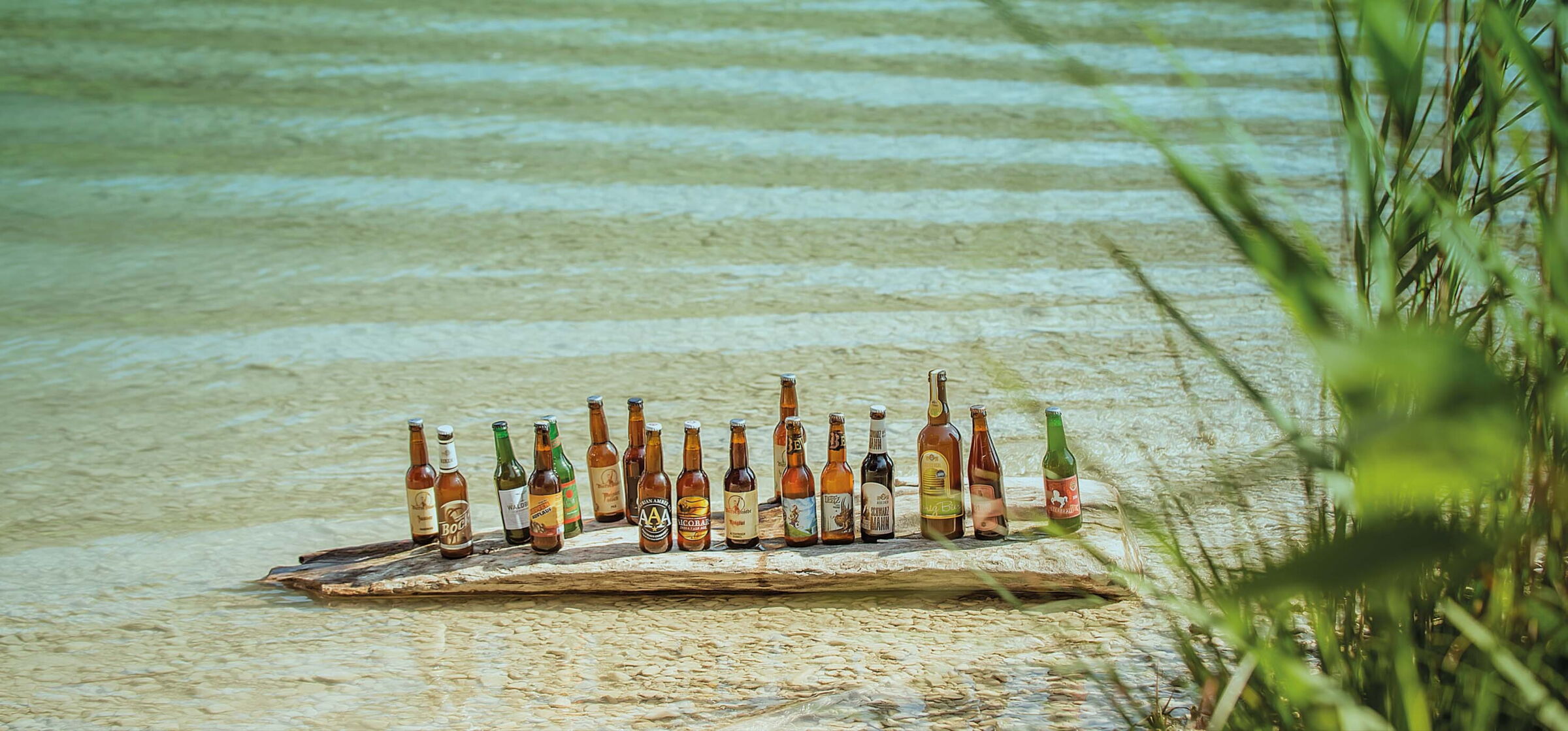 Viele verschiedene Bierflaschen auf einem Stein im Wolfgangsee