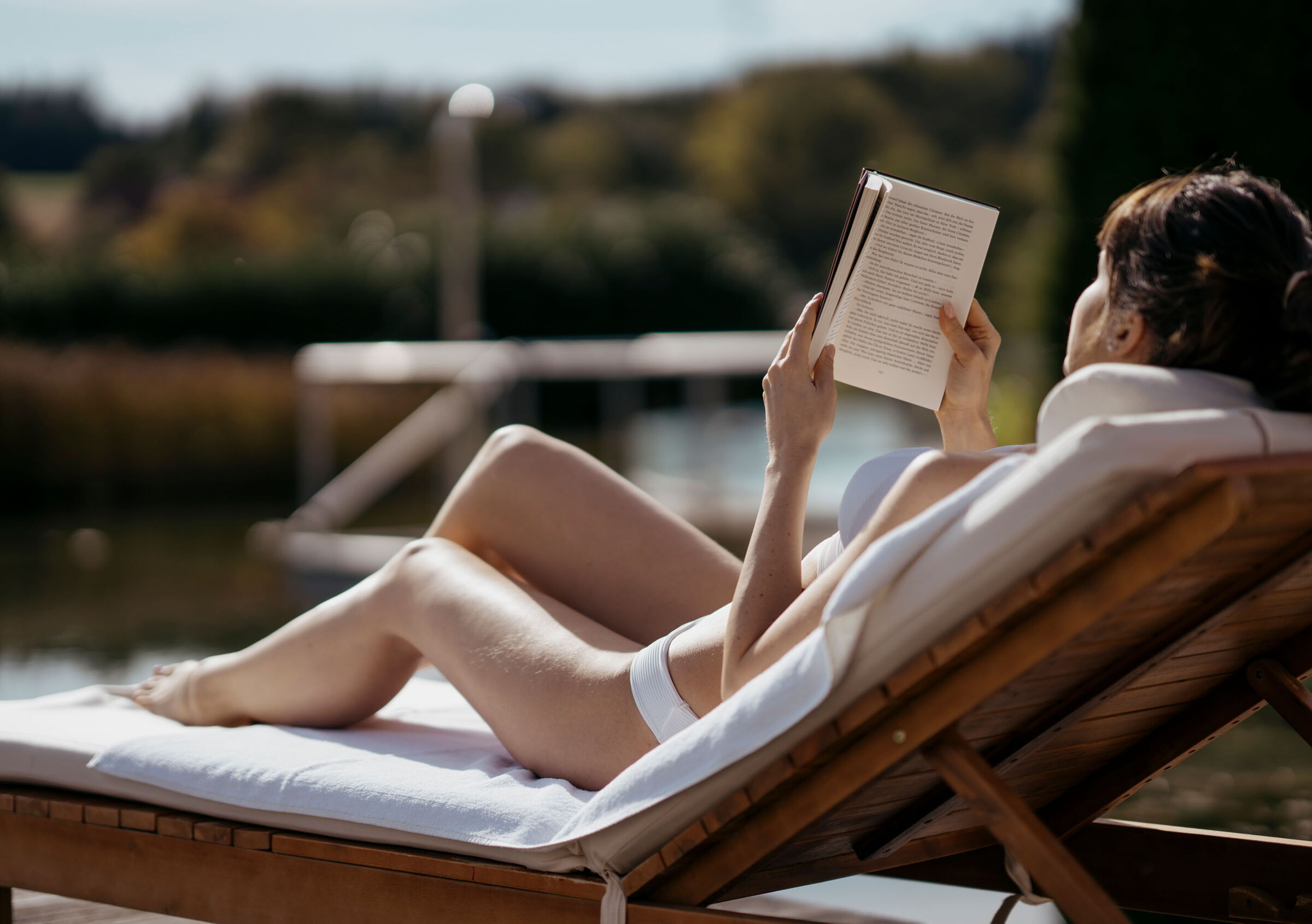 Eine Frau liegt auf einer Sonnenliege und liest ein Buch