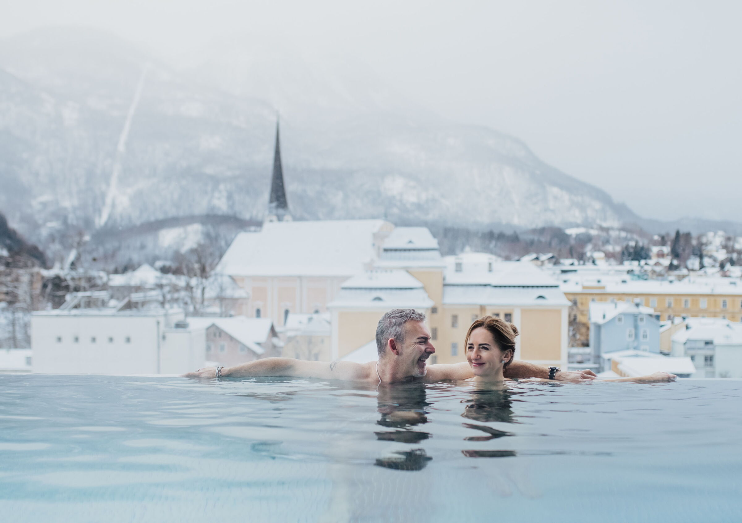 A couple in an infinity pool on the roof of a spa