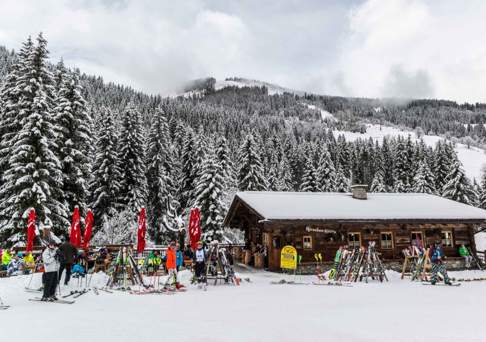 Kleine Hütte mit vielen geparkten Ski in verschneiter Pistenlandschaft