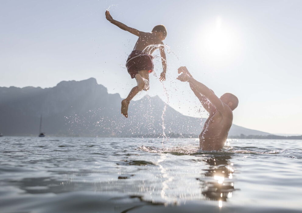 Vater wirft seinen Sohn beim Baden am See in den Wolfgangsee