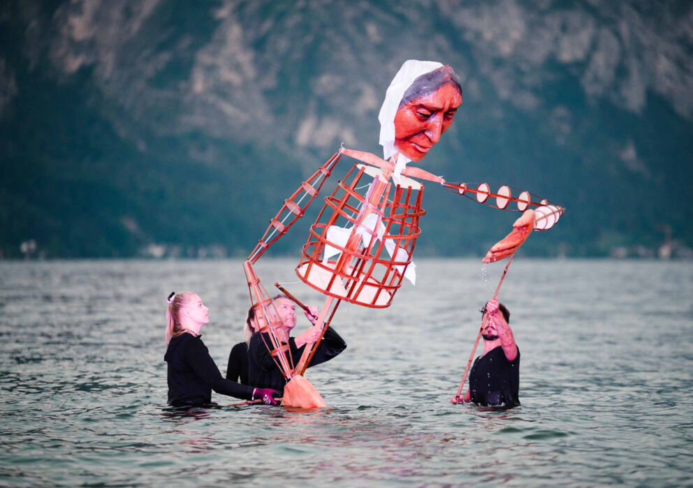 Mehrer Menschen bedienen eine Puppe für ein theaterstück im wasser