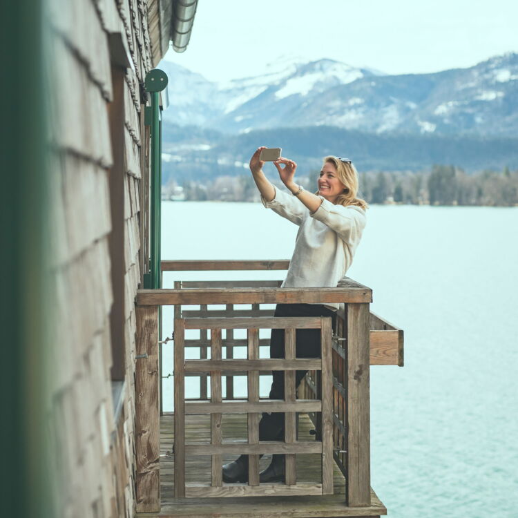 Woman photographing on a balcony by the lake