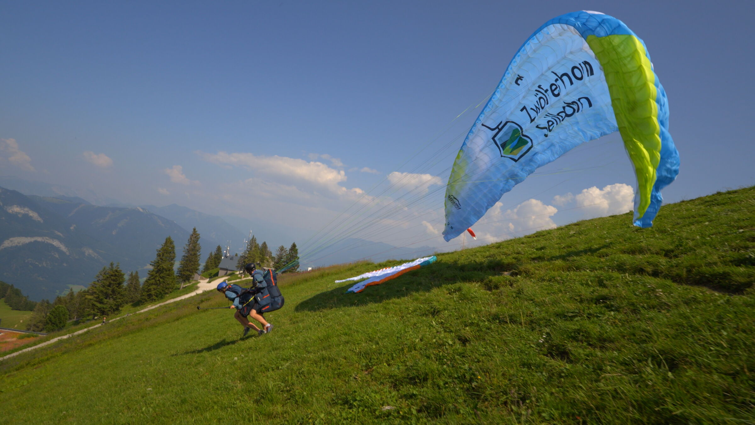 Man sieht Zwei Tandemparagleiter auf dem Zwölferhörn , bereit zum Abflug ©Flugschule Salzkammergut