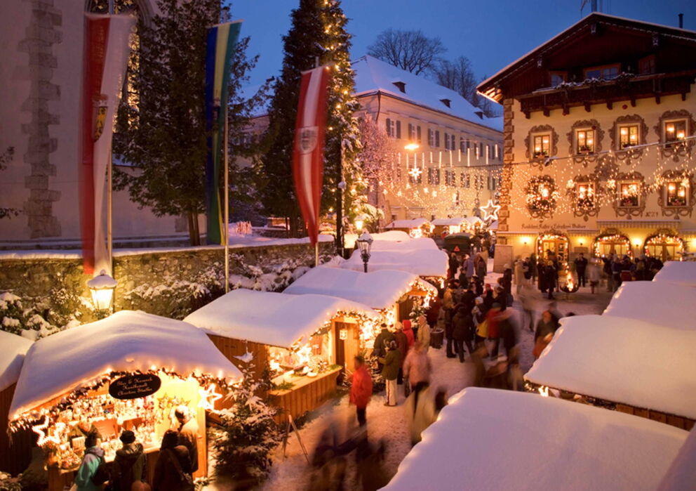 Schneebedeckte Hütten auf dem St. Wolfgang Weihnachtsmarkt im Salzkammergut, verbringen Sie die Feiertage in Ihrem Hotel zu Weihnachten, dem Weissen Rössl in Österreich.