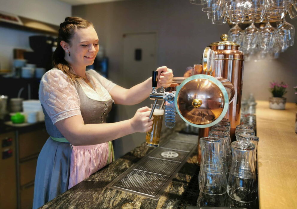 Kellnerin in traditionellen Dirndl am Bier abzapfen an einer Bar