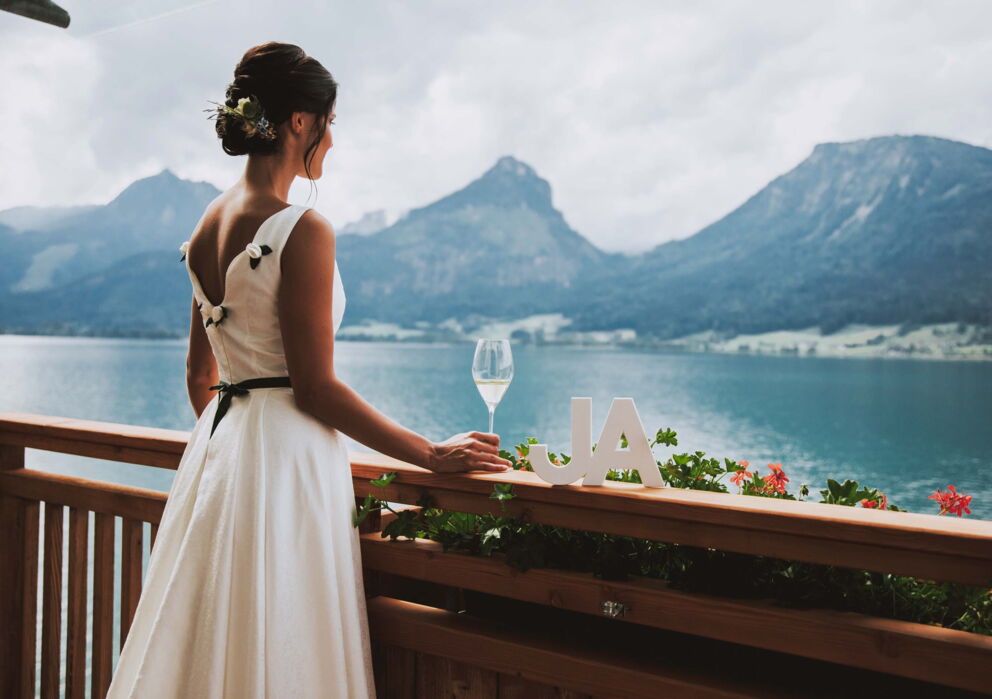 Braut in weißem Kleid auf einem Balkon am Wolfgangsee im Salzkammegut