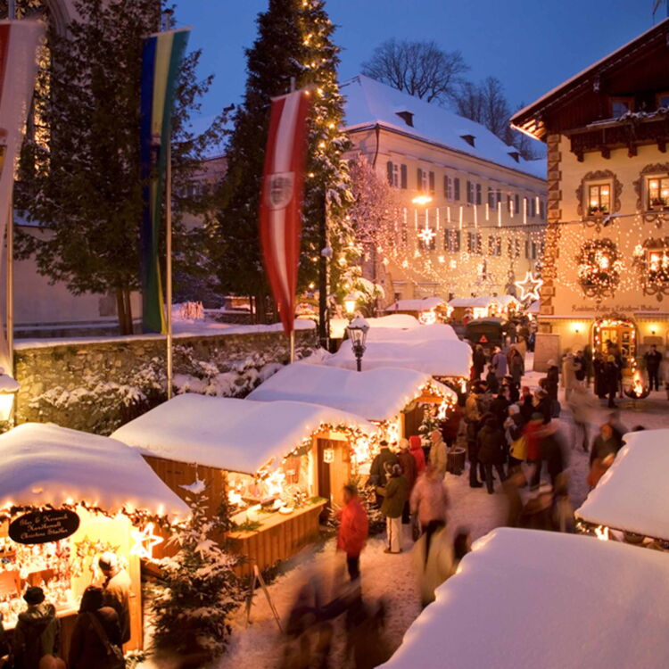 Schneebedeckte Hütten auf dem St. Wolfgang Weihnachtsmarkt im Salzkammergut, verbringen Sie die Feiertage in Ihrem Hotel zu Weihnachten, dem Weissen Rössl in Österreich.