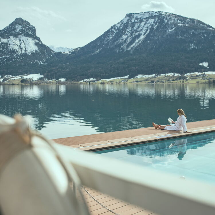 Reading woman at the heated lake bath with surrounding sugared mountain landscape