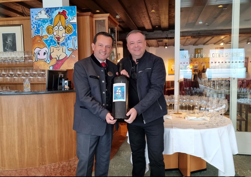 Zwei Männer mit einer großen Flasche Wein in einem Gasthof