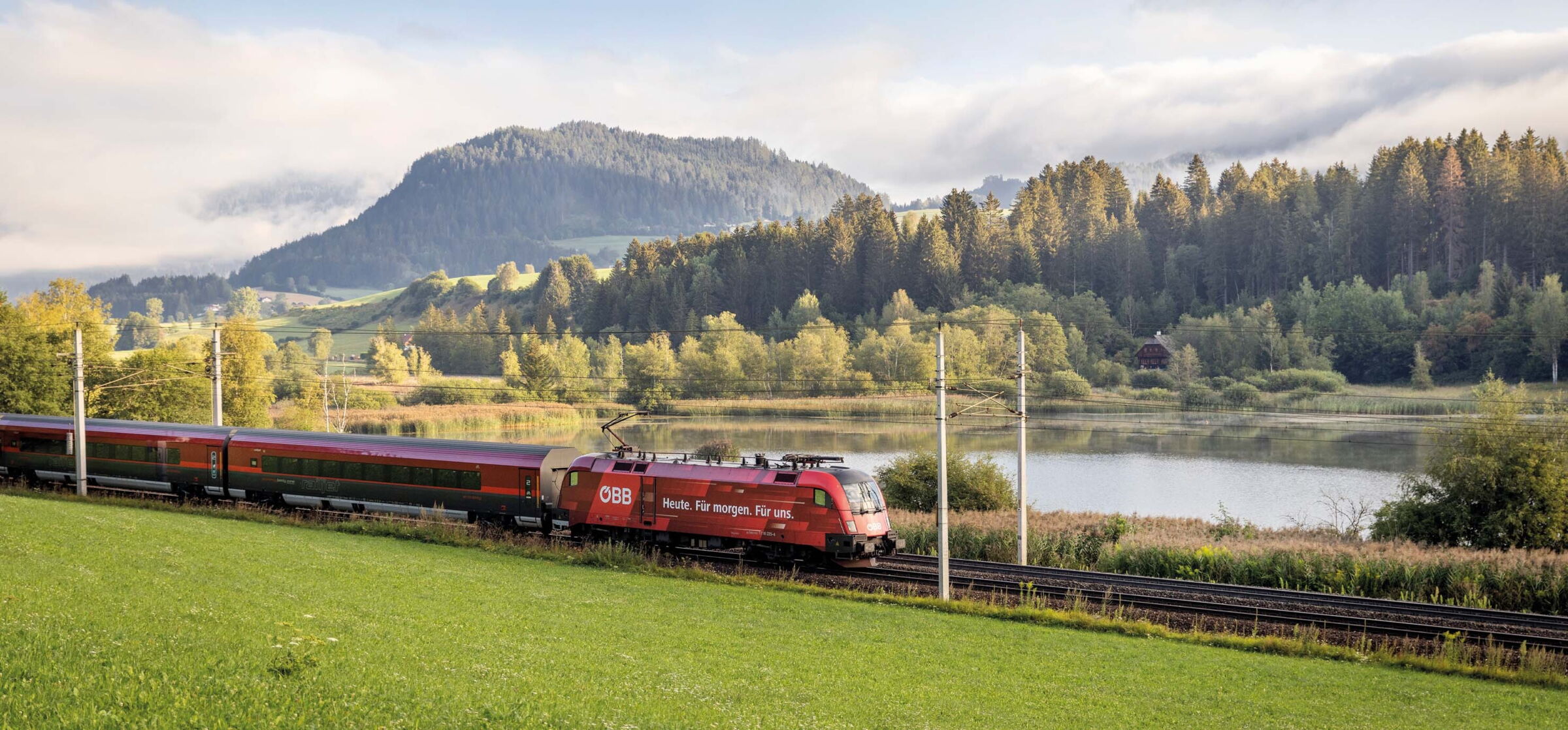 Der Railjet der ÖBB fährt an einem kleinen See in Österreich vorbei