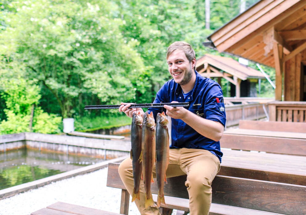 Mann mit drei Fischen an einer Stange