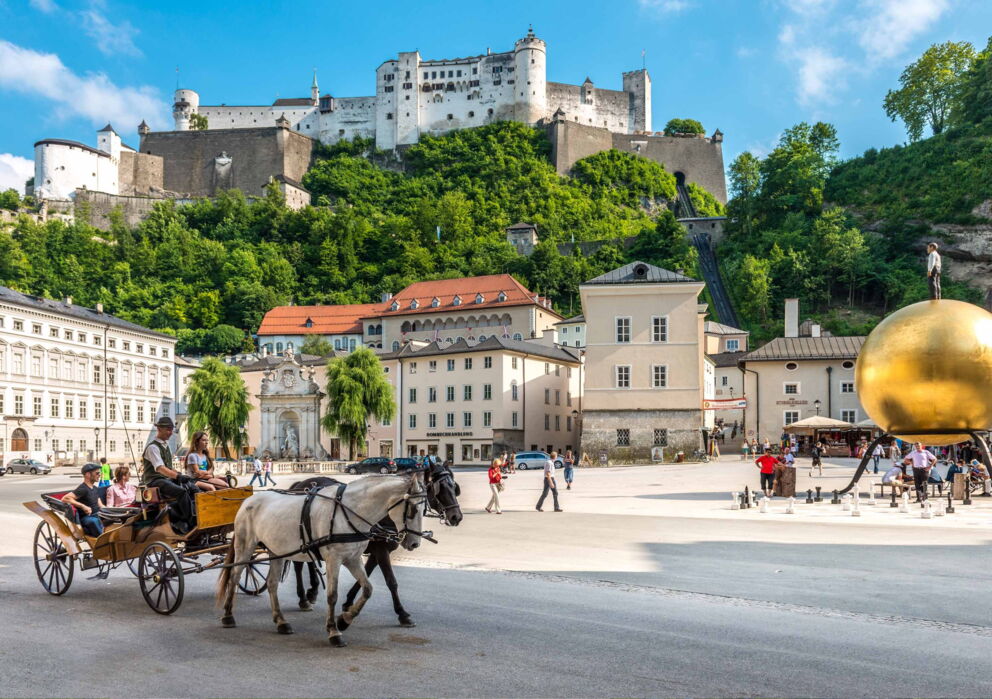 Sicht auf die Festung Hohensalzburg vom Kapitelplatz mit SAlzburger Fiakern und der goldenen kugel