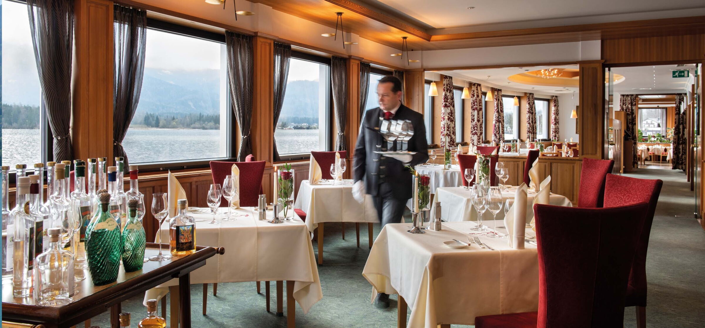 Ein Kellner geht durch die schön gedeckten Tische eines Restaurants am Wolfgangsee.