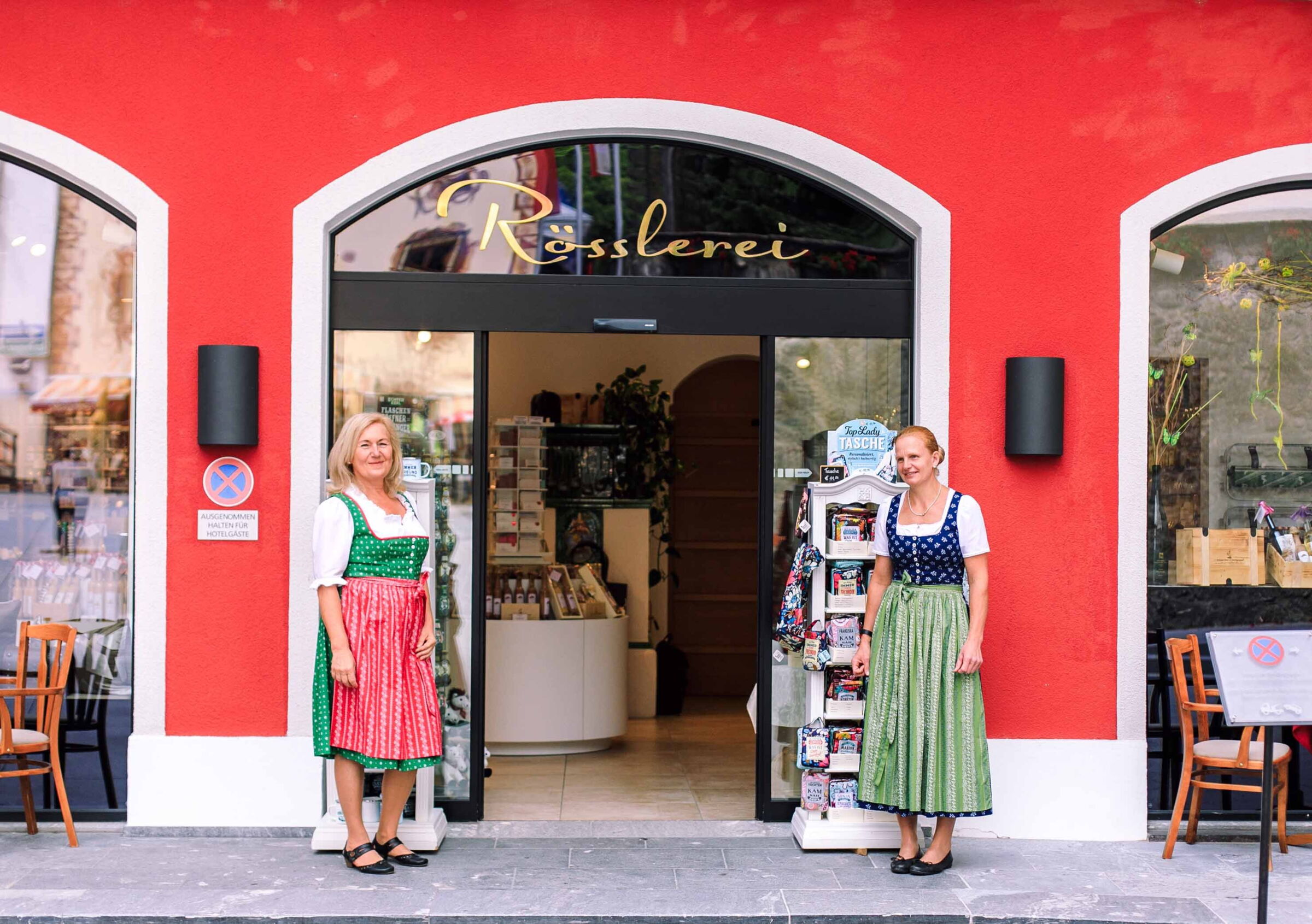 Two saleswomen stand in front of the entrance to the Rösslerei