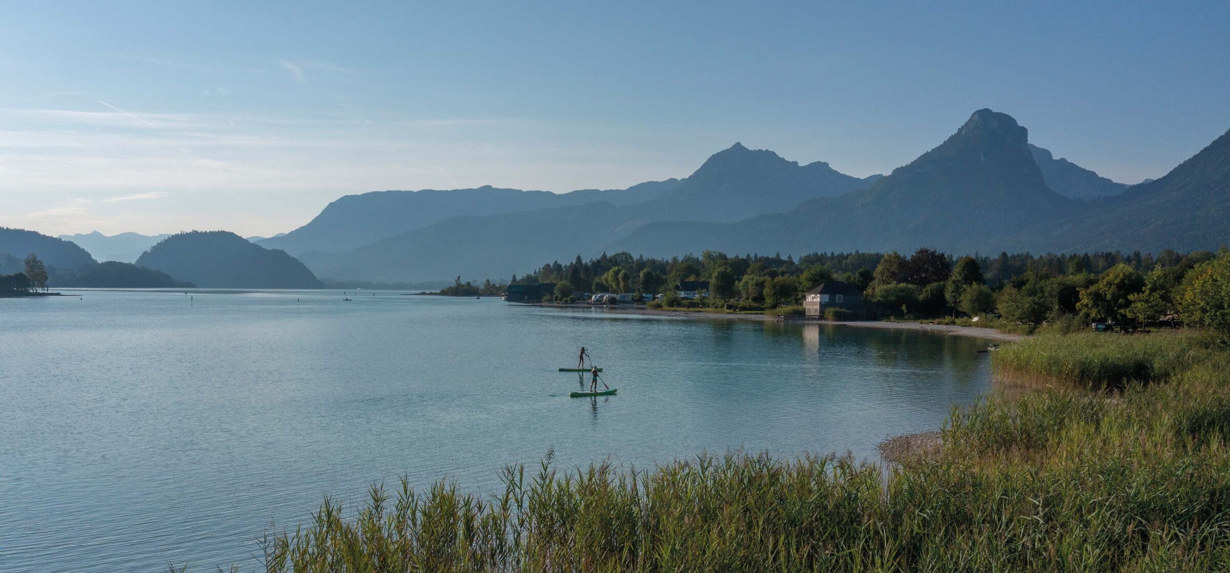 Two people stand-up paddleboarding on Lake Wolfgang