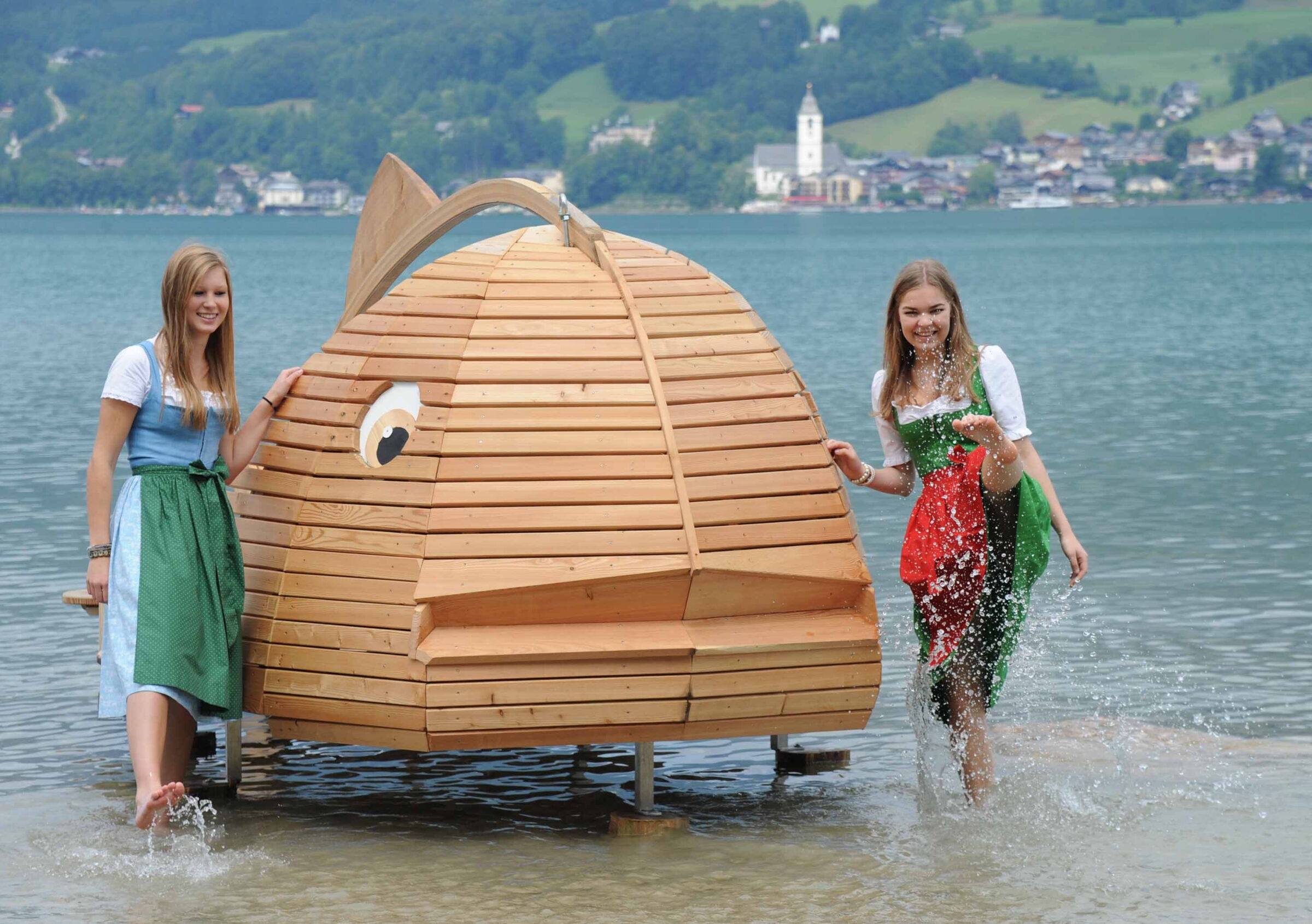 Zwei Mädchen neben einem Holzfisch