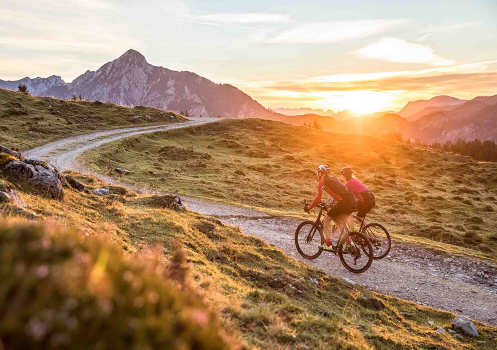 Two cyclists in the mountain landscape in the Salzkammergut during sunrise