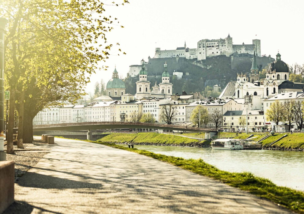 Walkway next to the Salzach river with a view of Salzburg's old town and the fortress