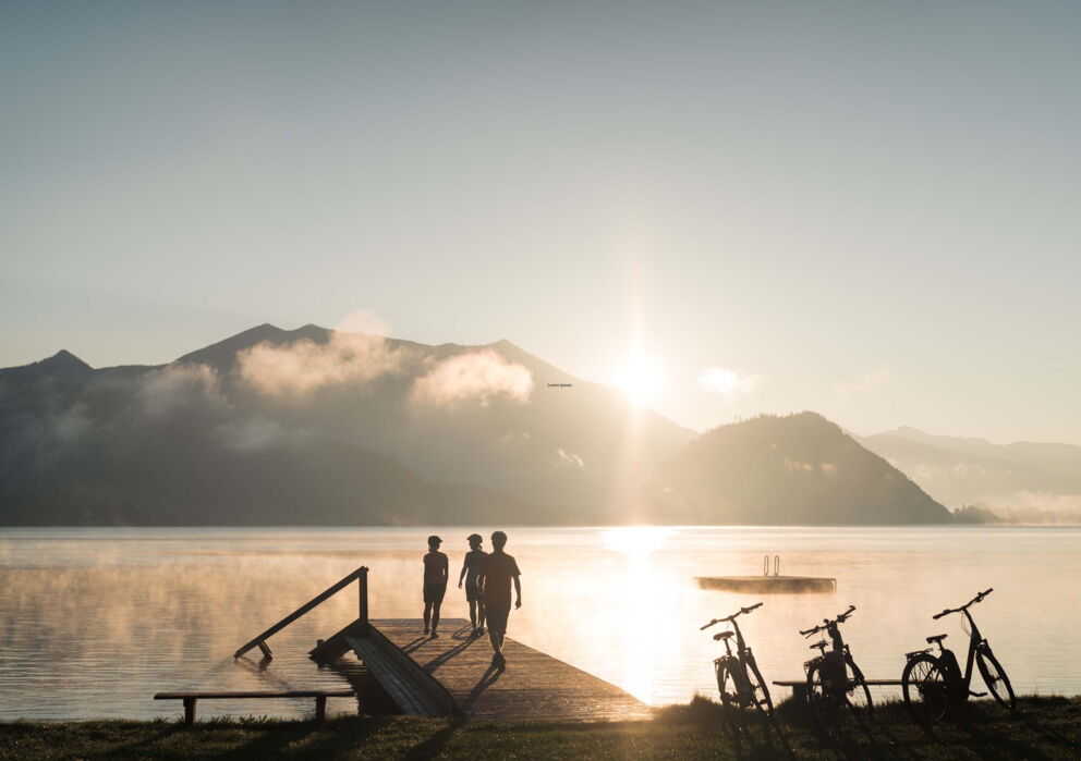 A group of friends on a jetty by the lake during sunset