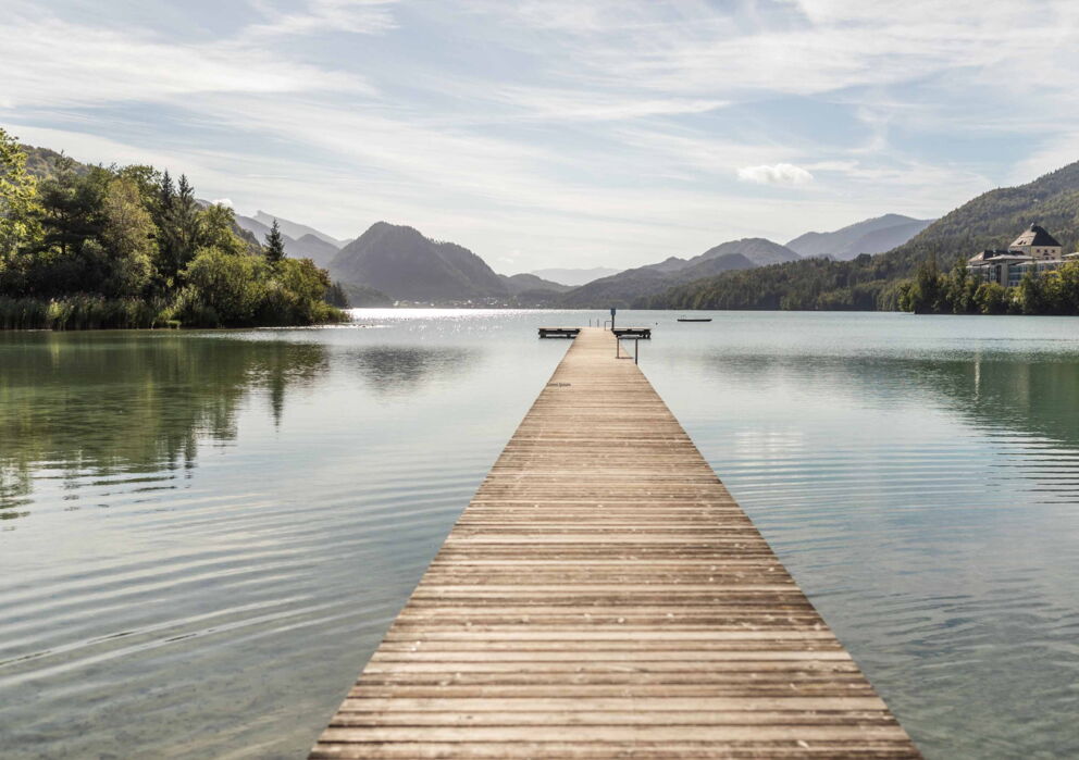 Long footbridge leading into the lake surrounded by impressive mountain scenery