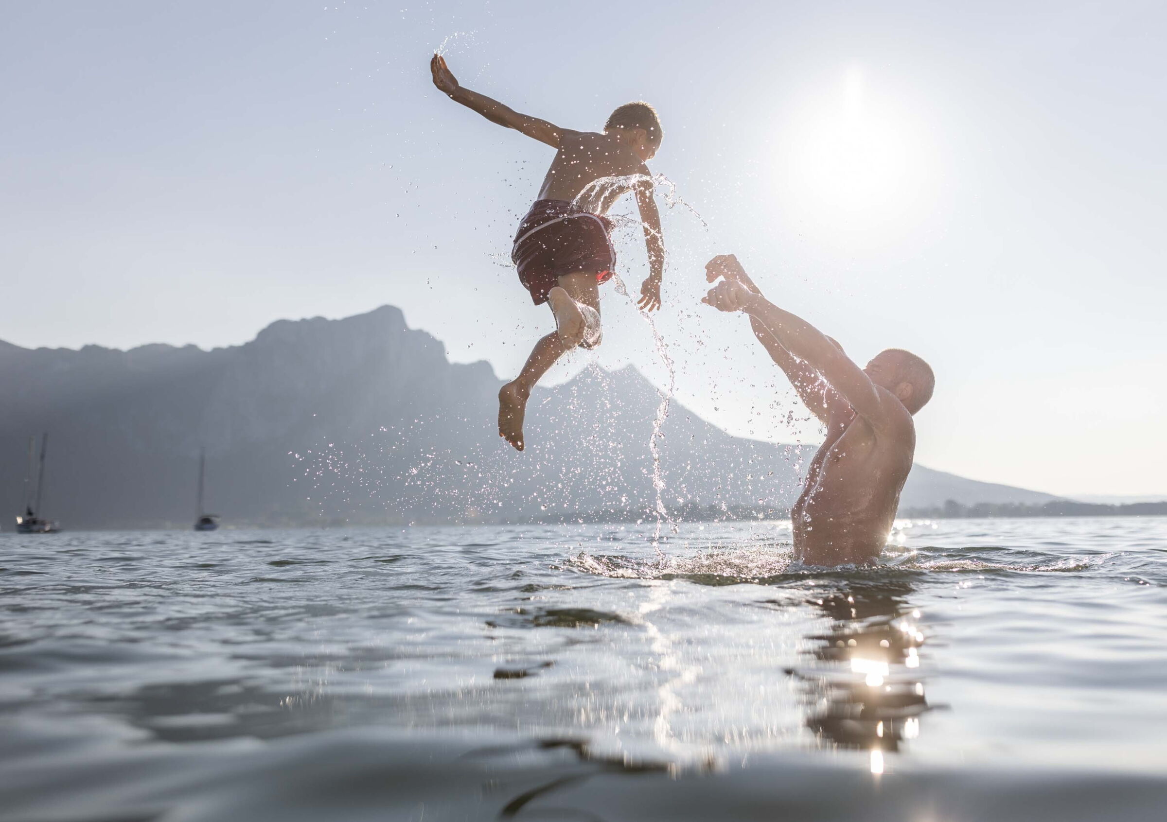 Vater wirft seinen Sohn beim Baden am See in den Wolfgangsee
