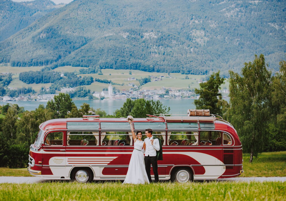 Frisch verheiratetes Paar vor einem Oldtimerbus vor dem Wolfgangsee