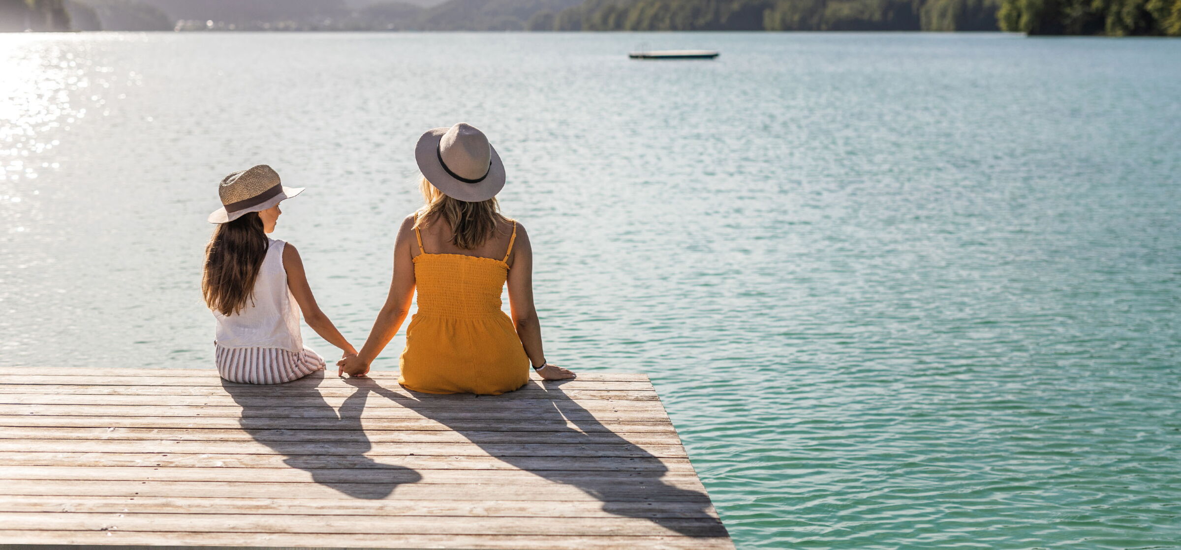 Mother and daughter sitting on the jetty on Lake Wolfgang at the Hotel Im Weissen Rössl