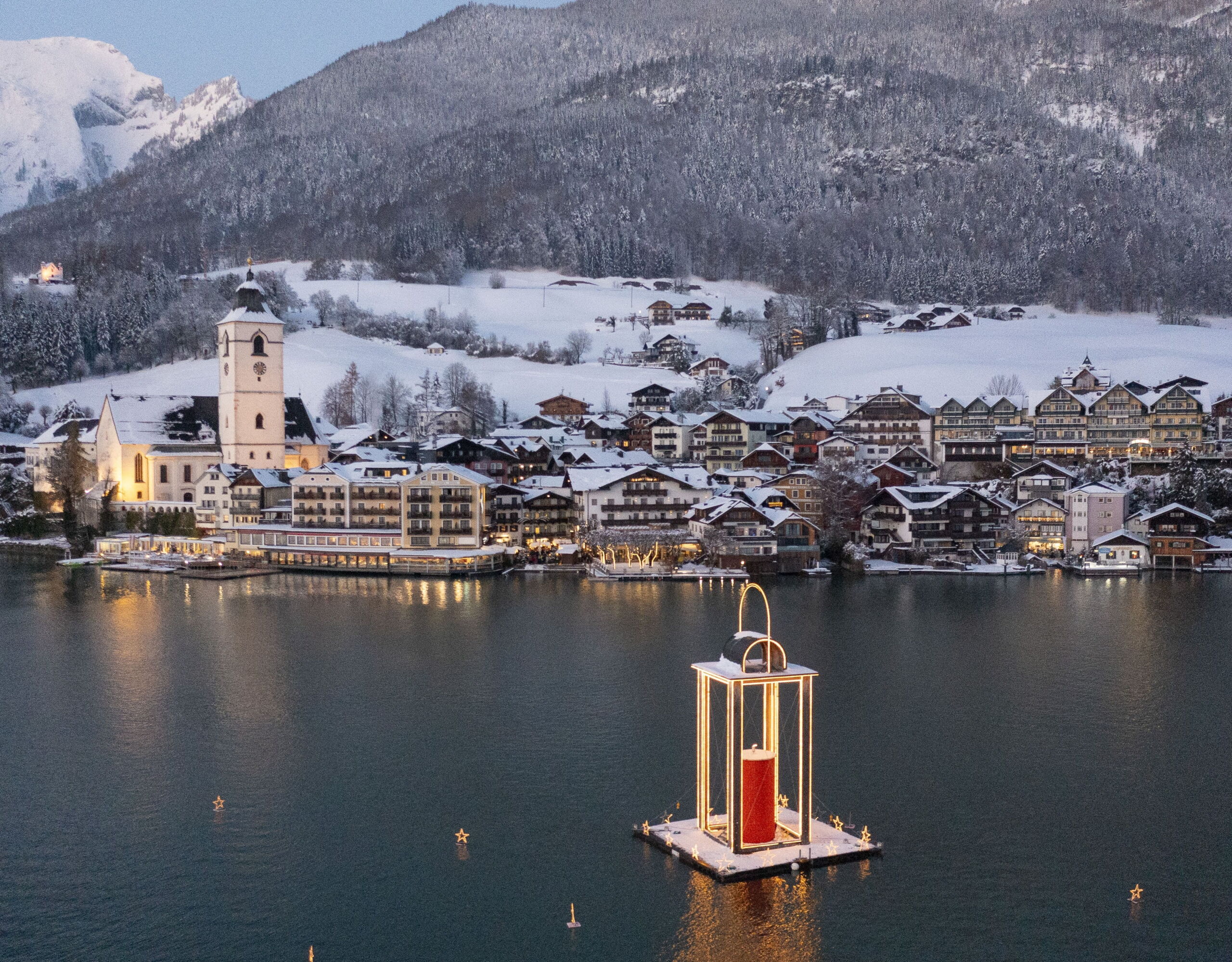 St. Wolfgang at Lake Wolfgang with snow-covered buildings, the lake and mountains in the background.