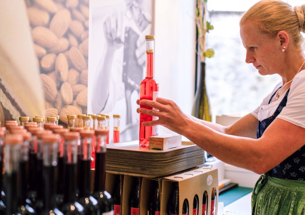 Eine Verkäuferin der Rösslerei Etikettiert eine Flasche