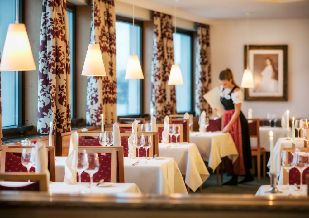 Kellnerin in traditioneller Tracht einen Tisch deckend in einem Restaurant