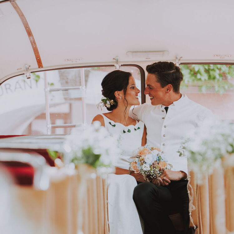 Frisch verheiratetes Ehepaar in einem schön geschmückten Oldtimerbus.
