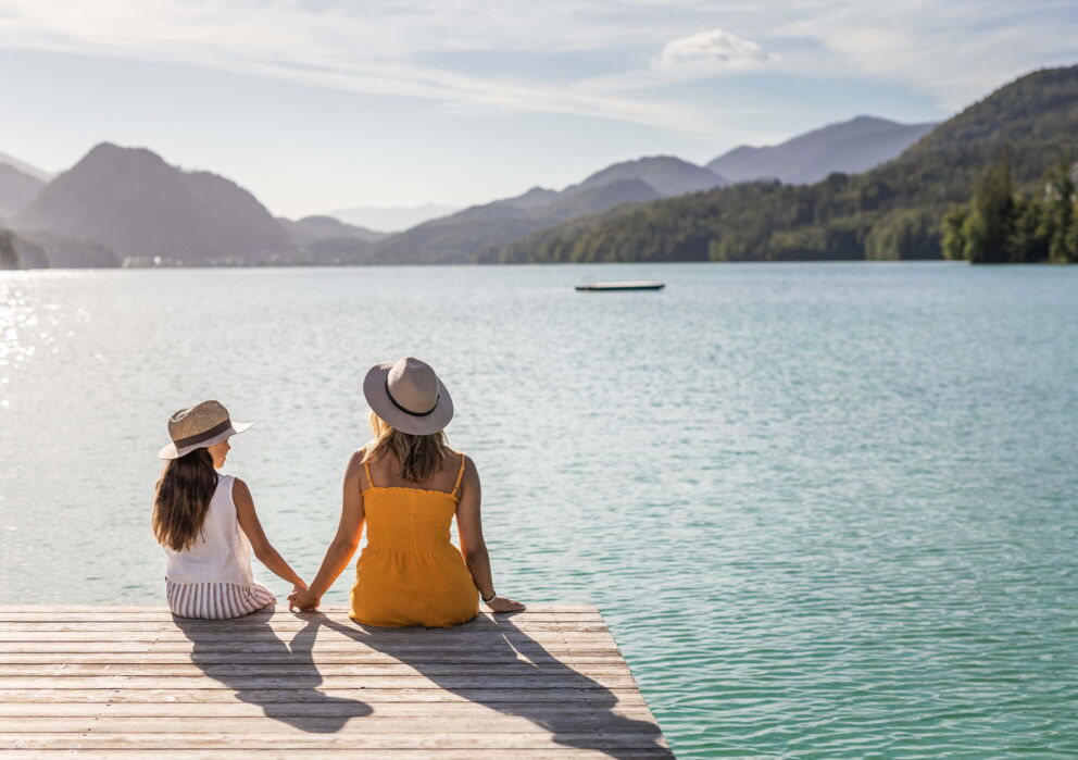Mutter und Tochter sitzend auf einem Steg am Wolfgangsee