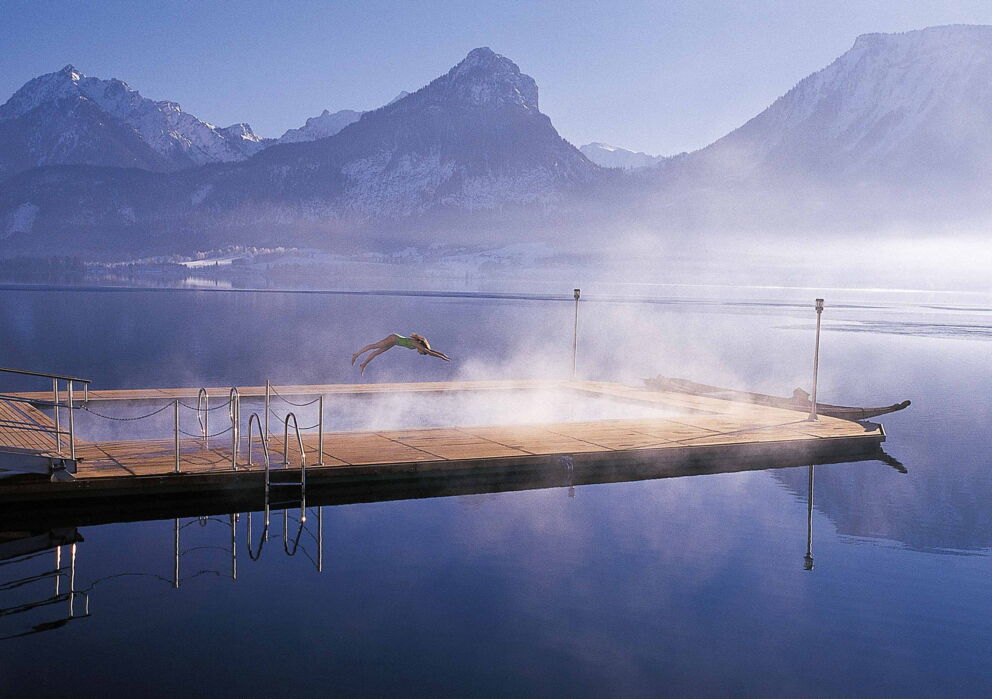 Dampfendes Seebad im Wolfgangsee in verschneiter Landschaft