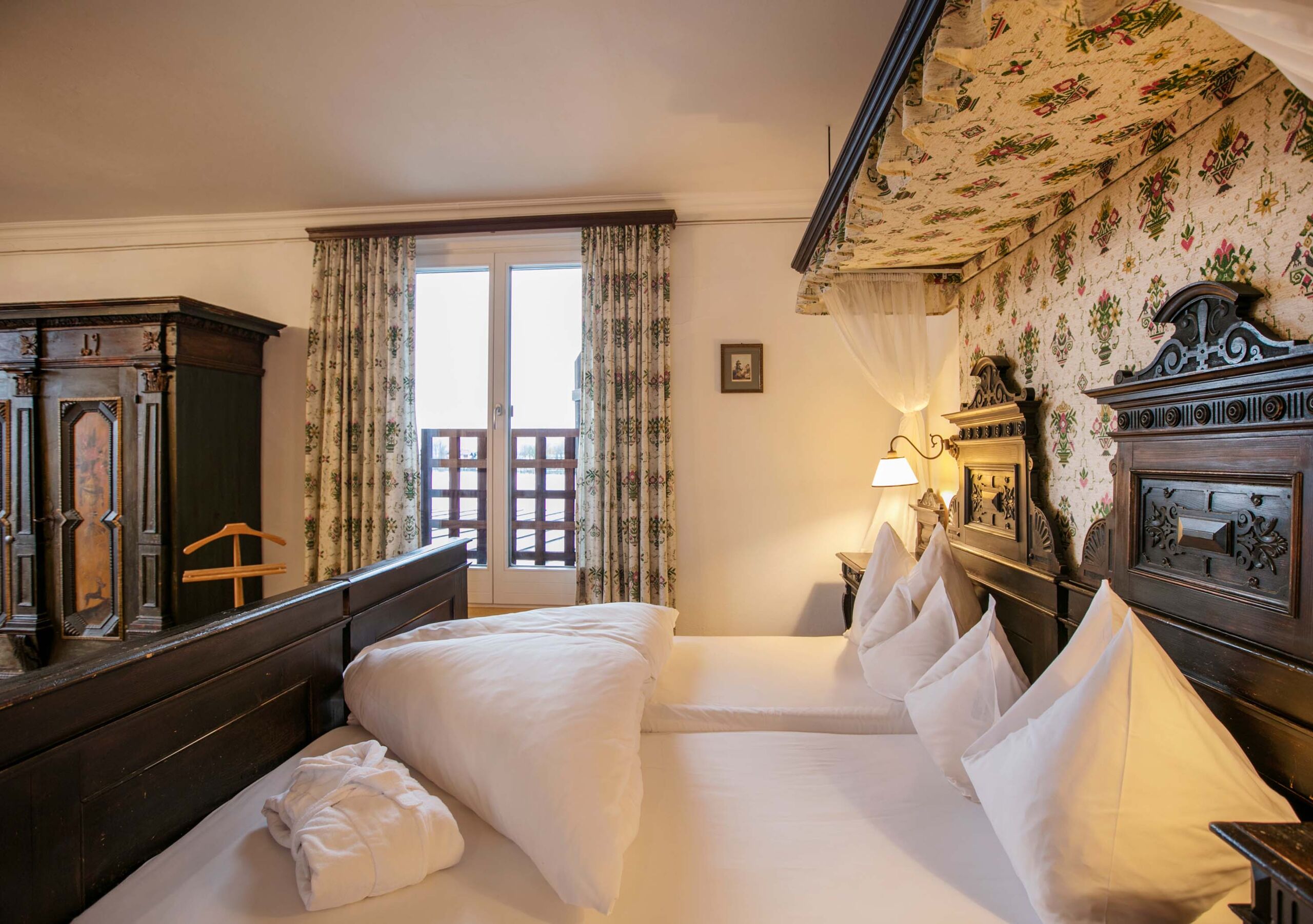 Zimmer mit Seebalkon im Weissen Rössl in altertümlichen Stil, mit einem schönen antiken Hand verzierten Holzschrank und einem ebenso schönen Altertümlich verziertes Bett