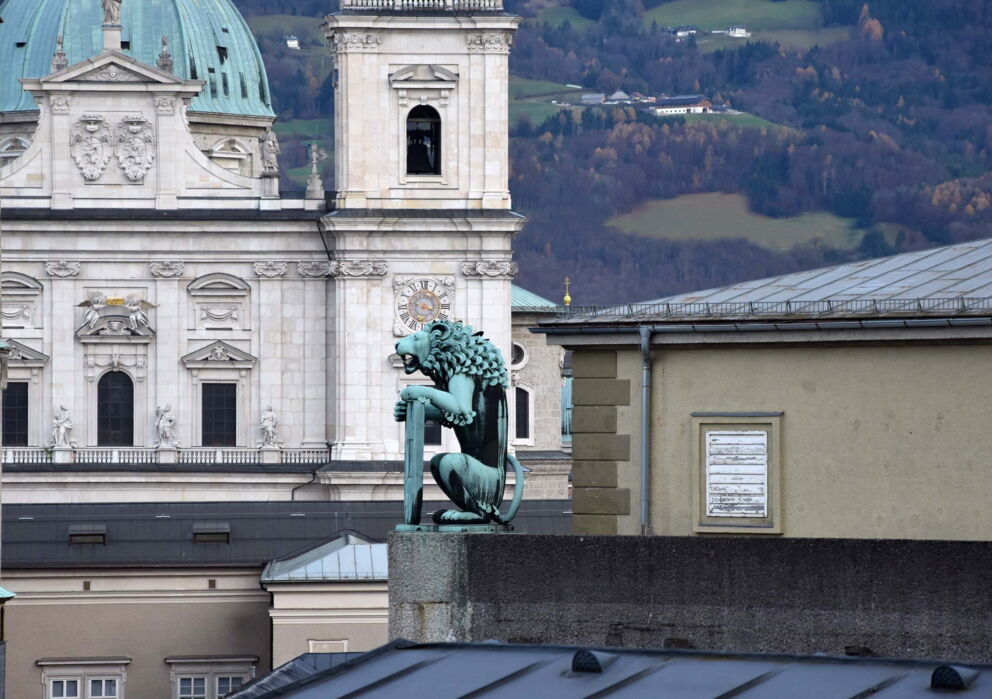Eine Löwenfigur auf dem Salzburger Festspiel Haus mit dem Salzburger Dom im hintergrund