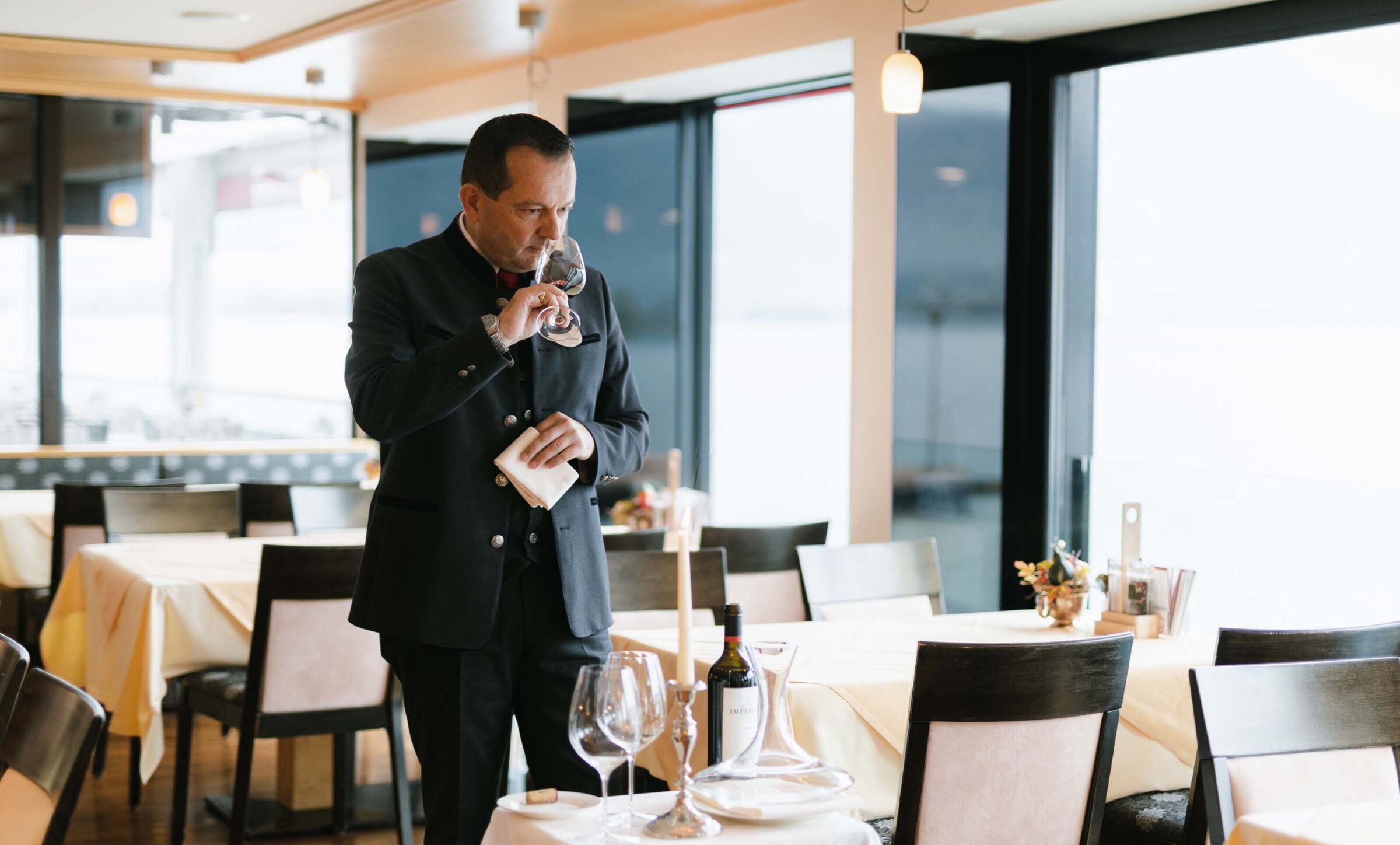 Sommelier with a glass and bottle of wine at the Weissen Rössl