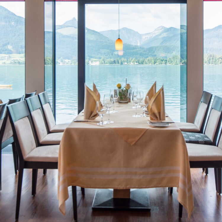 Nehmen Sie Platz an einem Tisch mit Aussicht auf das Wasser Im Weissen Rössl und schlendern Sie durch die Rössl Speisekarte.