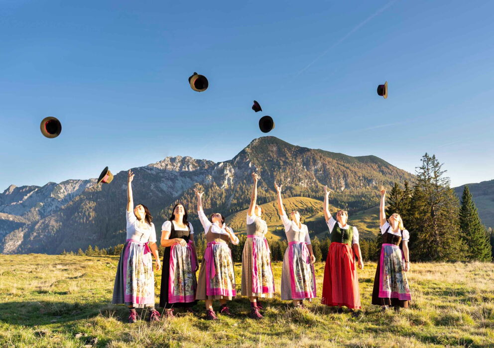 Eine Gruppe junger Frauen in traditionellen Dirndl am Hüte schmeißen
